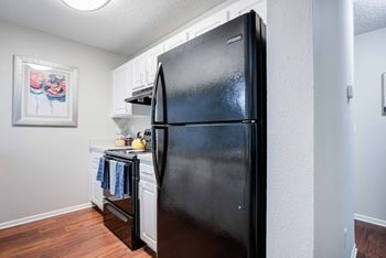 A black refrigerator in a kitchen with a picture on the wall.